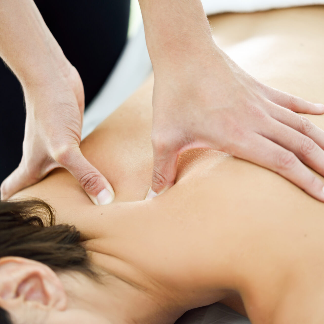 Young woman receiving a back massage in a spa center. Female patient is receiving treatment by professional therapist.